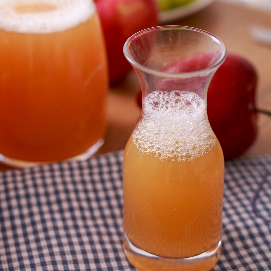Apfelessig in Karaffe mit frischen Äpfeln als natürliche Zutat für Vedi Boost Stoffwechsel-Drink